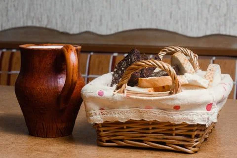 Wicker basket with different sliced bread and a jug of milk on the table. Hom Stock Photos