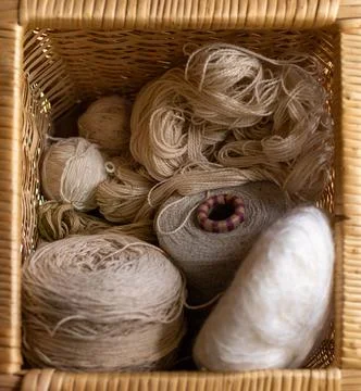 Wicker basket with different types of yarns and wool. Stock Photos