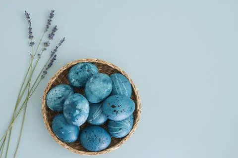 Wicker basket with Easter blue eggs and a bouquet of lavender on a light blue Stock Photos