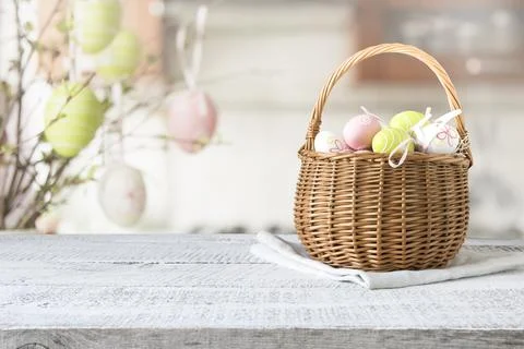 Wicker basket with easter colorful eggs on kitchen wooden table. Spring Stock Photos