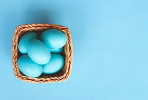 Wicker basket with easter eggs on a blue background Stock Photos
