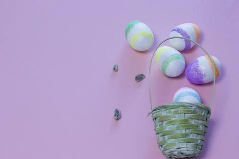 Wicker basket with Easter eggs on color background. Stock Photos