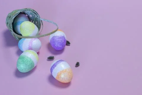 Wicker basket with Easter eggs on color background. Stock Photos