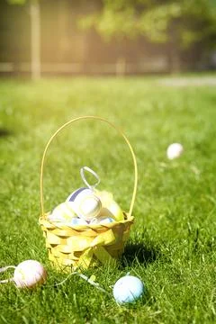 A wicker basket of Easter eggs on a green lawn, a sunny day. Stock Photos