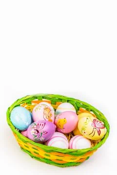 Wicker basket with Easter eggs hand painted on white tabletop background Stock Photos