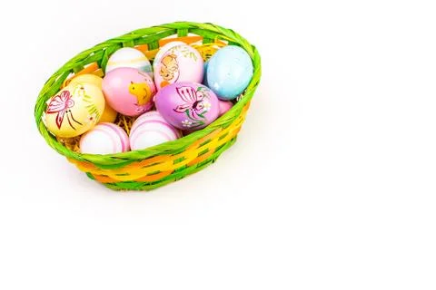 Wicker basket with Easter eggs hand painted on white tabletop background Stock Photos