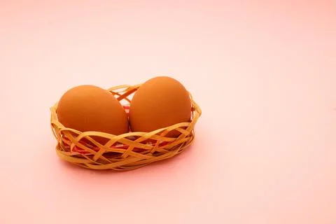 Wicker basket with Easter eggs on pink background Foto stock
