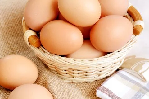 Wicker basket with eggs on a linen tablecloth Stock Photos