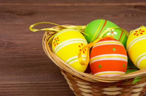A wicker basket filled with easter eggs on a rustic background. Stock Photos