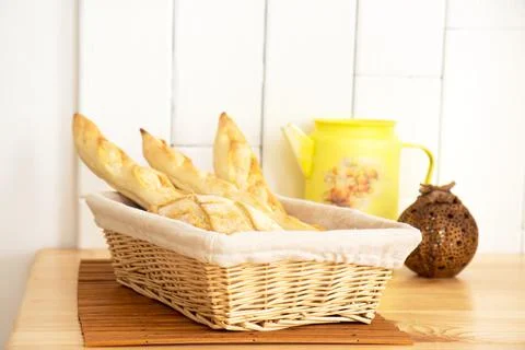 Wicker basket with fresh baguettes on wooden table Stock Photos