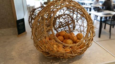 Wicker Basket with Fresh Oranges on Table in Restaurant Interior 스톡 사진