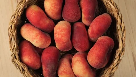 Wicker basket full of fresh peaches rotating on a wooden table Stock Footage 340526370