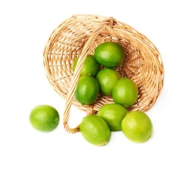 Wicker basket full of multiple ripe limes, composition isolated over the white Stock Photos