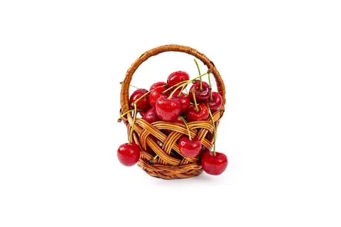 Wicker basket full of red cherry fruits, isolated on white background Foto stock