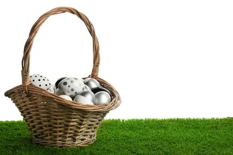 Wicker basket of painted Easter eggs on green lawn against white background.  Stock Photos