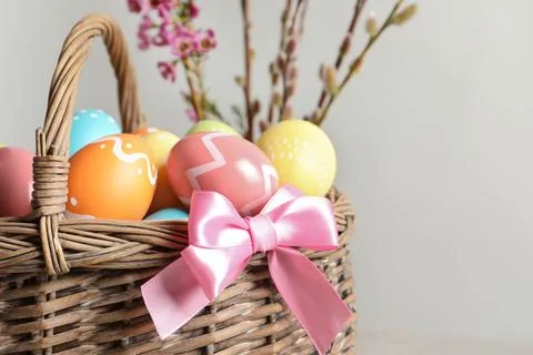 Wicker basket with painted Easter eggs and flowers on color background, close 스톡 사진