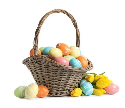 Wicker basket with painted Easter eggs and spring flowers on white background Stock Photos
