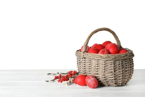 Wicker basket with painted red Easter eggs on table against white background, Stock Photos