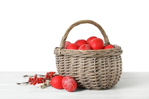 Wicker basket with painted red Easter eggs on table against white background Stock Photos