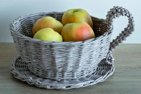 Wicker basket in the shape of a tea cup with apples Foto stock