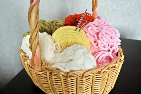 Wicker basket with various knitting threads and knitting needles sticking out Stock Photos