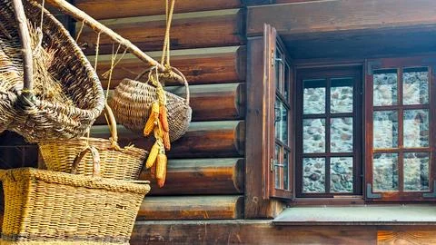 Wicker baskets and dried corn hanging by a rustic wooden house window Stock Photos
