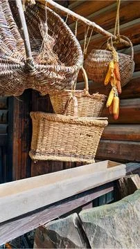 Wicker baskets and dried corn hanging on wooden wall, rustic countryside Stock Photos