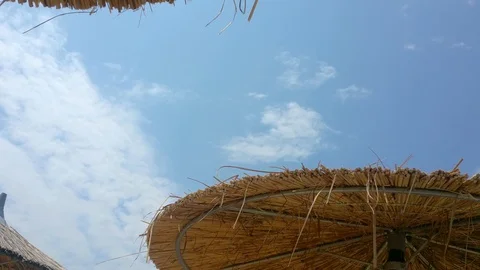 Wicker beach umbrellas under blue sky with clouds, Nea Iraklia, Halkidiki Greece Stock Footage 113259934