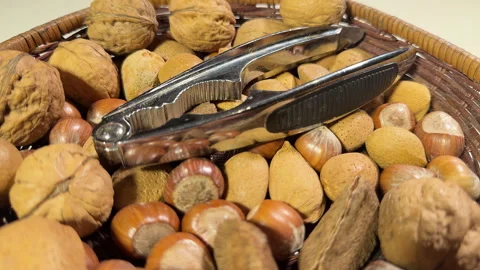 A wicker bowl of unshelled nuts with nutcrackers on top. Stock Footage 295142002