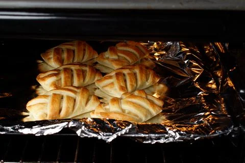 Wicker buns with an apple on a baking sheet. Ruddy buns only from the oven. Stock Photos