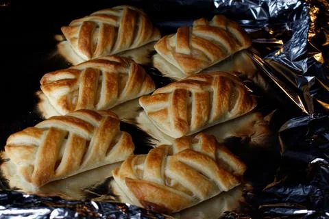 Wicker buns with an apple on a baking sheet. Ruddy buns only from the oven. Stock Photos