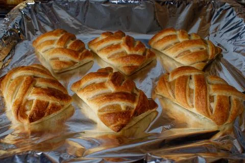 Wicker buns with an apple on a baking sheet. Ruddy buns only from the oven. Stock Photos