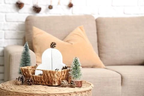 Wicker coffee table with pine cones and mini fir trees in festive living room Stock Photos