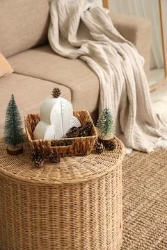 Wicker coffee table with pine cones and mini fir trees in festive living room Stock Photos