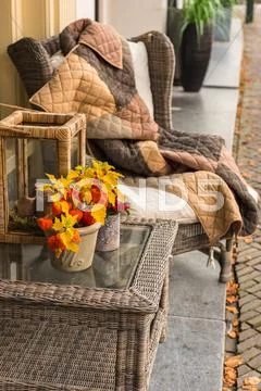 Wicker cozy armchair with blanket and small wicker glass table Stock Photos