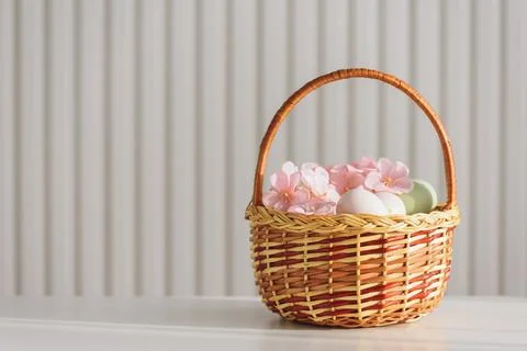 Wicker Easter Basket with Pastel Eggs and Flowers. Soft Spring Decor Foto stock
