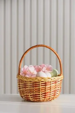 Wicker Easter Basket with Pastel Eggs and Flowers. Soft Spring Decor Stock Photos