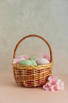 Wicker Easter Basket with Pastel Eggs and Flowers. Soft Spring Decor Stock Photos