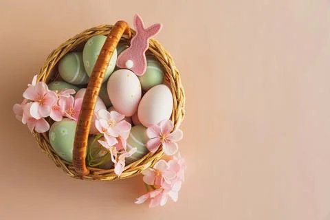 Wicker Easter Basket with Pastel Eggs and Flowers. Soft Spring Decor 스톡 사진