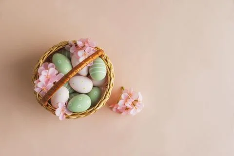 Wicker Easter Basket with Pastel Eggs and Flowers. Soft Spring Decor Stock Photos