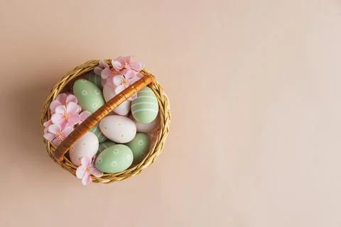 Wicker Easter Basket with Pastel Eggs and Flowers. Soft Spring Decor Stock Photos
