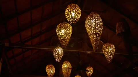 Wicker lamps gently swinging, casting golden shadows across wooden surfaces Stock Footage 308679108