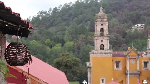 Wicker lantern hanging on red tile roof with church and mountain Stock Footage 287495087