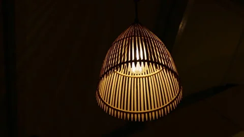 Wicker pendant lamp swaying in a dark room Видео 341961995