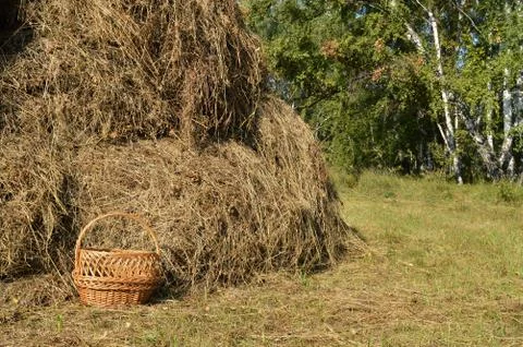 Wicker picnic basket and a haystack - a beautiful rural background in Sunny s Stock Photos