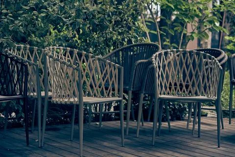 Wicker plastic chairs outdoors, against a background of green bushes. The cafe Fotos de archivo