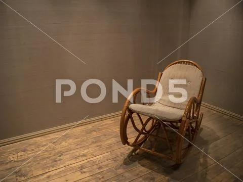Wicker rocking chair in empty room with wooden floor Stock Photos