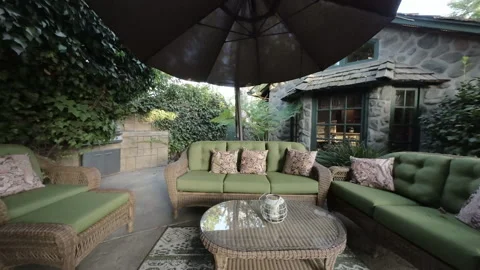 Wicker sofas with green cushions under a patio umbrella Stock Footage 345543670