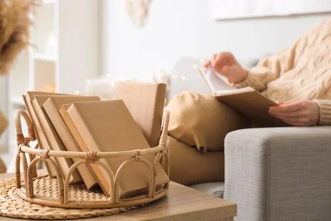Wicker tray with stack of books on table at home, closeup Stock Photos