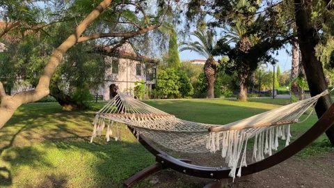 Wicker white hammock is tied between two trees in beautiful garden. Tropical Stock Footage 242846826